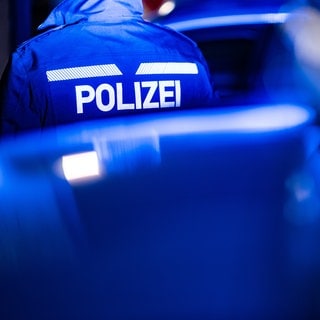 blaulicht und Polizist in Uniform bei Nacht - Symbolbild für Polizei ermittelt nach Kellerbränden auf Brandstiftung in Kaiserslautern