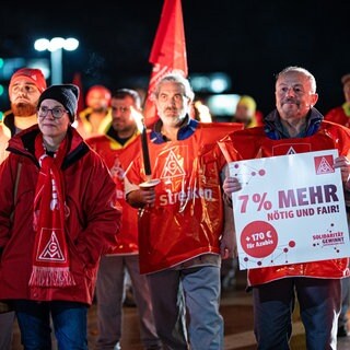 Streikende der IG Metall halten Fackeln und Transparent hoch - IG Metall streikt in der Westpfalz