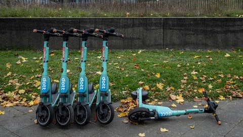 Geparkte und umgestürzte Dott E-Scooter im Herbst.