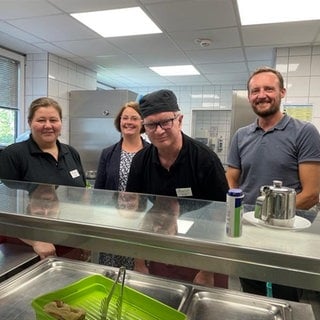 Das Foto zeigt die Küche des SWR-Studios in Kaiserslautern. Links Martina Kalker - Koordinatorin des Gastrobereichs, daneben die stellvertrende Leiterin der Westpfalz-Werkstätten Carolin Witt, Peter Poltz - Mitarbeiter in der SWR-Kantine und rechts steht der Leiter der Werkstätten, Jan Löffler. 