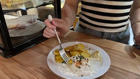 Hüttenbesucherin isst Bratkartoffeln mit weißen Käse.