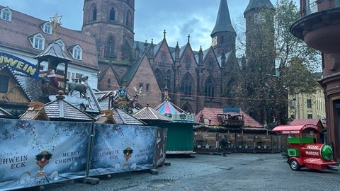 Festlich dekorierte Hütten und Stände stehen in der Innenstadt von Kaiserslautern bereit. Der Weihnachtsmarkt 2024 steht in den Startlöchern und ist noch von Zäunen umgeben. 