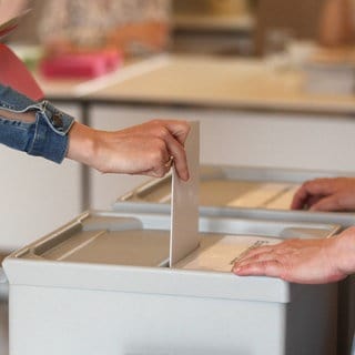 Eine Frau wirft ihren Stimmzettel in eine Wahlurne.