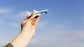 Eine Person hält ein kleines Flugzeug in der Hand. 