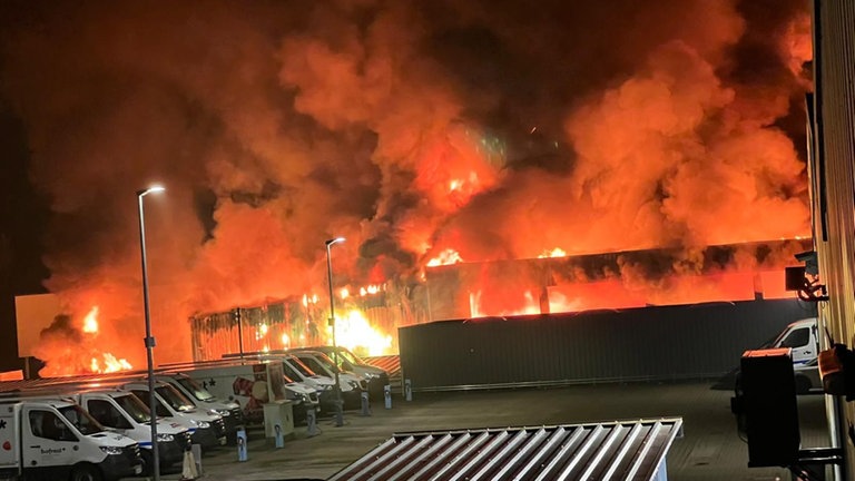 Eine brennende Halle in der Nacht im Feuerschein - Feuer in Wäscherei in Landstuhl