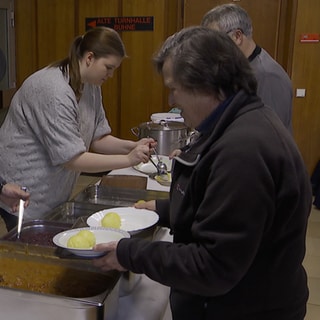 Helfer geben beim Weihnachtsessen für Wohnungslose in Kaiserslautern Klöße, Rotkohl und Gulasch aus.