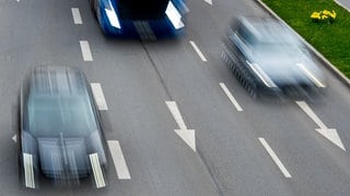 Zwei Autos und ein Lkw sind auf der Autobahn unterwegs.