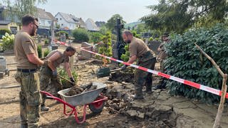 Auf dem Friedhof am Ahrtor in Bad Neuenahr-Ahrweiler sind Kräfte der Bundeswehr mit den Aufräumarbeiten beschäftigt. Mit Schippen und Schubkarren werden Schlamm und Treibgut entfernt.