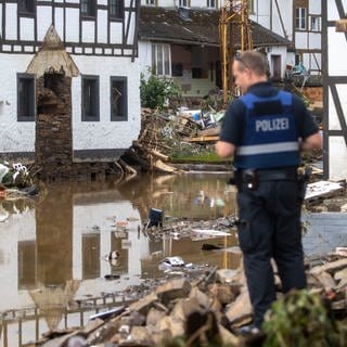 Ein Polizist macht sich ein Bild von der Lage im zerstörten Ort Schuld in der Eifel.