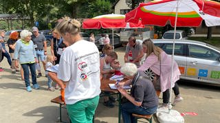 Arbeiterwohlfahrt hat in Ahrbrück einen Stand aufgebaut, an dem Betroffene der Hochwasserkatastrophe im Ahrtal an einem Tisch Anträge auf Soforthilfe ausfüllen