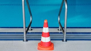 Eine Pylone steht in einem Hallenbad an einer Leiter des Schwimmerbeckens. Das Schwimmbad ist wegen der Coronakrise bis auf weiteres geschlossen. 