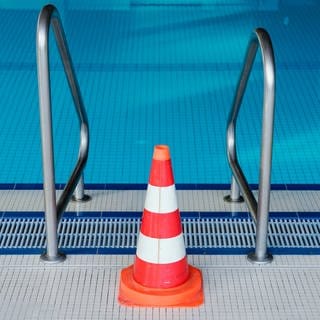 Eine Pylone steht in einem Hallenbad an einer Leiter des Schwimmerbeckens. Das Schwimmbad ist wegen der Coronakrise bis auf weiteres geschlossen. 