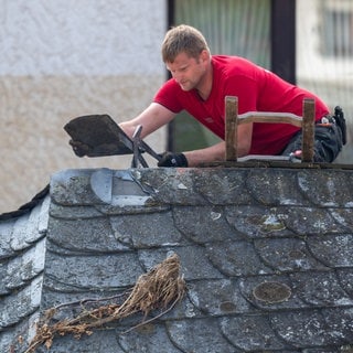 Ein Dachdecker arbeitet an einem der Häuser, die von der Flutkatastrophe beschädigt wurden