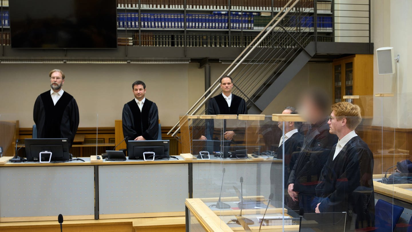 Jetzt wird das Urteil erwartet: Der Angeklagte (2.v.r), dem vorgeworfen wird, 1991 einen Brandanschlag auf ein Asylbewerberwohnheim in Saarlouis verübt zu haben, steht zu Prozessbeginn zwischen seinen Anwälten.