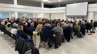 Rund 200 Menschen sitzen bei einem Infoabend in der Rhein-Mosel-Halle zu einer geplanten Flüchtlingsunterkunft in Koblenz