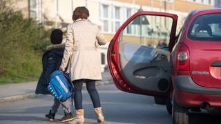 Eine Mutter bringt ihr Kind mit dem Auto zur Schule