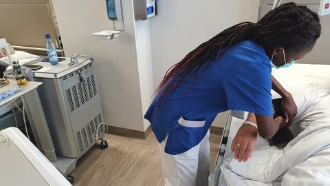 Ausländische Pflegerin versorgt Arm eines Patienten