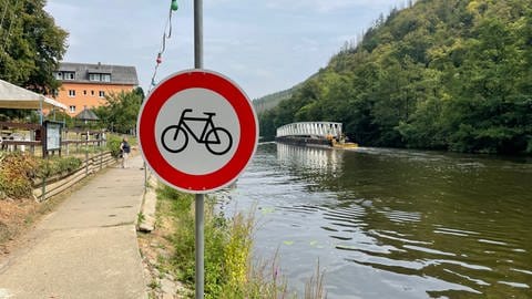 Radfahren verboten Schild, im Hintergrund eine Brücke, die über die Lahn auf einem Ponton gezogen wird.