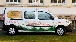 ein weißer Kleinwagen mit der Aufschrift "unser Dorfauto" Im Rhein-Hunsrück-Kreis werden drei Jahre lang solche E-Dorfautos getestet. 