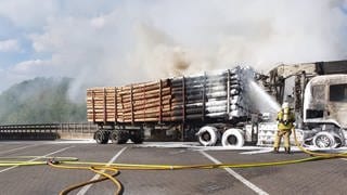 Löscharbeiten an brennendem Holztransporter