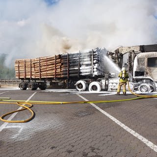 Löscharbeiten an brennendem Holztransporter