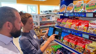 Mit einem Tablet wird ein Supermarkt-Regal abscannt