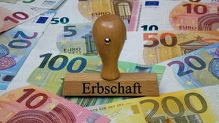 Zahlreiche Euro-Geldscheine und ein Stempel mit dem Aufdruck "Erbschaft"