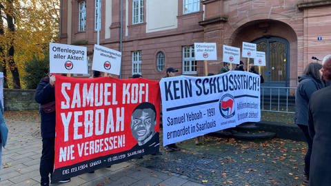 Vor dem Gerichtsgebäude haben die Antifa und die Gruppe "Aktion 3. Welt Saar" mit Plakaten und Transparenten für eine umfassende Aufklärung des Falls demonstriert.