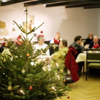 Menschen sitzen gemeinsam an Weihnachten zusammen und feiern. Vereine und Organisationen in Koblenz und der Region organisieren kleine Weihnachtsfeiern für alleinstehende Menschen, die an Heiligabend sonst allein wären.