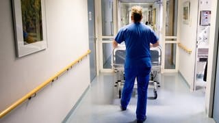 Krankenpfleger schiebt leeres Bett in Klinik