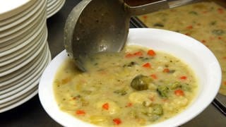 Eine Schöpfkelle liegt in einem Teller mit Suppe