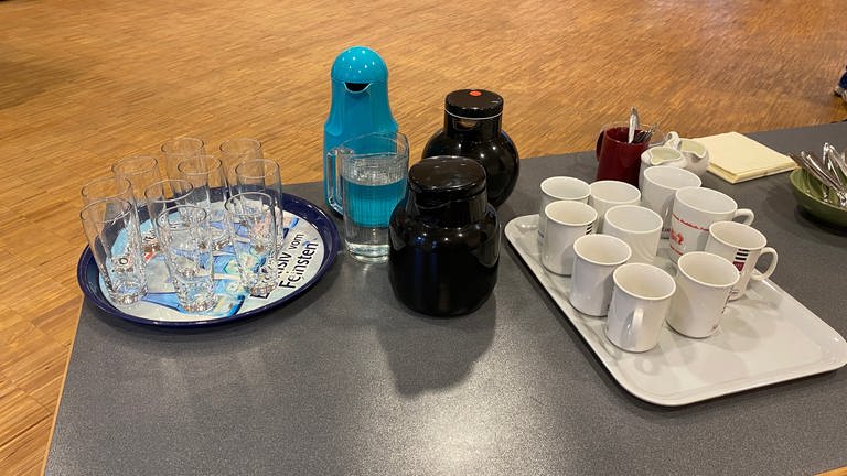 Blick auf ein Tablett mit Gläsern, Wasserflaschen, einer Kaffeekanne und Tassen
