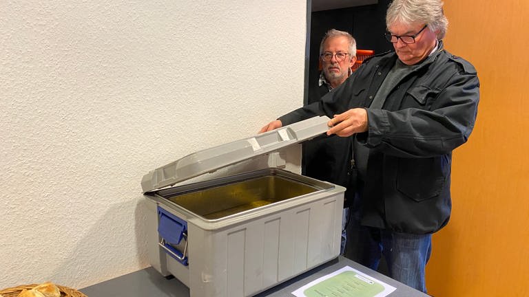 Zwei Männer blicken auf einen Warmhaltecontainer mit heißer Suppe: Suppe für alle in Neuwied