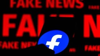 Smartphone mit Facebook-Logo und der Schrift "Fake News" im Hintergrund