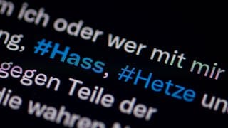 Auf dem Bildschirm eines Smartphones sieht man die Hashtags (#) Hass und Hetze in einem Twitter-Post.
