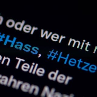 Auf dem Bildschirm eines Smartphones sieht man die Hashtags (#) Hass und Hetze in einem Twitter-Post.