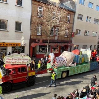 Ein Motivwagen beim Koblenzer Rosenmontagszug 2023: Ein deutscher Michel, dazu ein Schild mit der Aufschrift "Erbsen, Linsen, Kohl und Gras - Michel macht darauf Biosgas!"