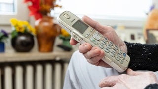 Eine Seniorin hält ein Telefon.