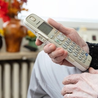 Eine Seniorin hält ein Telefon.