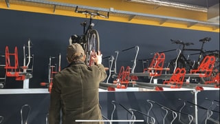 Ein Mann hebt sein Fahrrad im Fahrradparkhaus in Koblenz in einen Fahrradständer