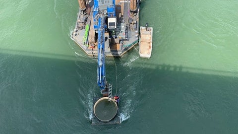 Über ein ins Wasser eingelassenes Rohr mit knapp vier Metern Durchmesser wird jeder Verdachtspunkt durch jeweils zwei Taucher freigesaugt und inspiziert.