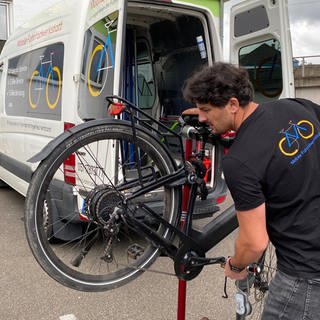 Nico untersucht bei einem Termin mit seiner mobilen Fahrradwerkstatt das E-Bike eines Kunden.