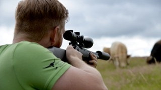 Rinderzüchter Christian Grommes deutet in einer gestellten Szene an, wie er mit dem "Weideschuss" ein Tier direkt auf der Weide tötet, um es später zu schlachten. 