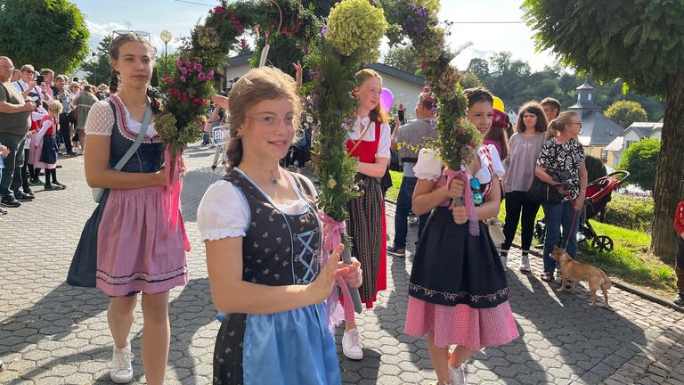 Zwei Mädchen in bayrischen Trachten tragen gemeinsam eine Blumengirlande beim Alm-Abtrieb in Niederelbert im Westerwald.