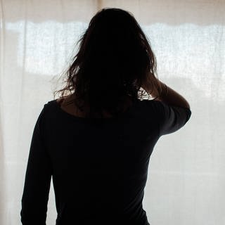Eine Frau schaut aus einem Fenster mit Vorhang: Nach dem Mord an einer mutmaßlichen Prostituierten in Koblenz schlägt eine Beratungsstelle Alarm - die Gewalt gegen die Frauen nehme deutlich zu.
