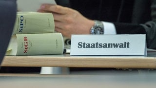 Ein Schild mit der Aufschrift «Staatsanwalt» neben zwei Strafgesetzbüchern