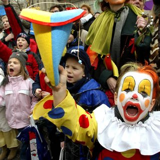 Lauthals "Kamelle" rufend, stehen Kinder am Straßenrand beim Karnevalsumzug.