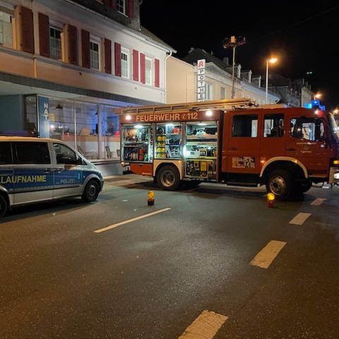 Sankt Goarshausen im Dunkeln nach dem Unfall: Ein Feuerwehrwagen steht quer auf der Bahnhofstraße und sperrt den Verkehr ab, ein Polizeiauto steht davor.