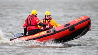Zwei Retter der DLRG sitzen in einem Schlauchboot - bei Hamm an der Sieg wurde eine Familie mithilfe eines Bootes aus einem Steilhang gerettet.