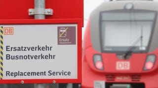 Blick auf einen Zug der Deutschen Bahn im Zusammenhang mit einem Schild das auf einen möglichen Ersatzverkehr hinweist. 